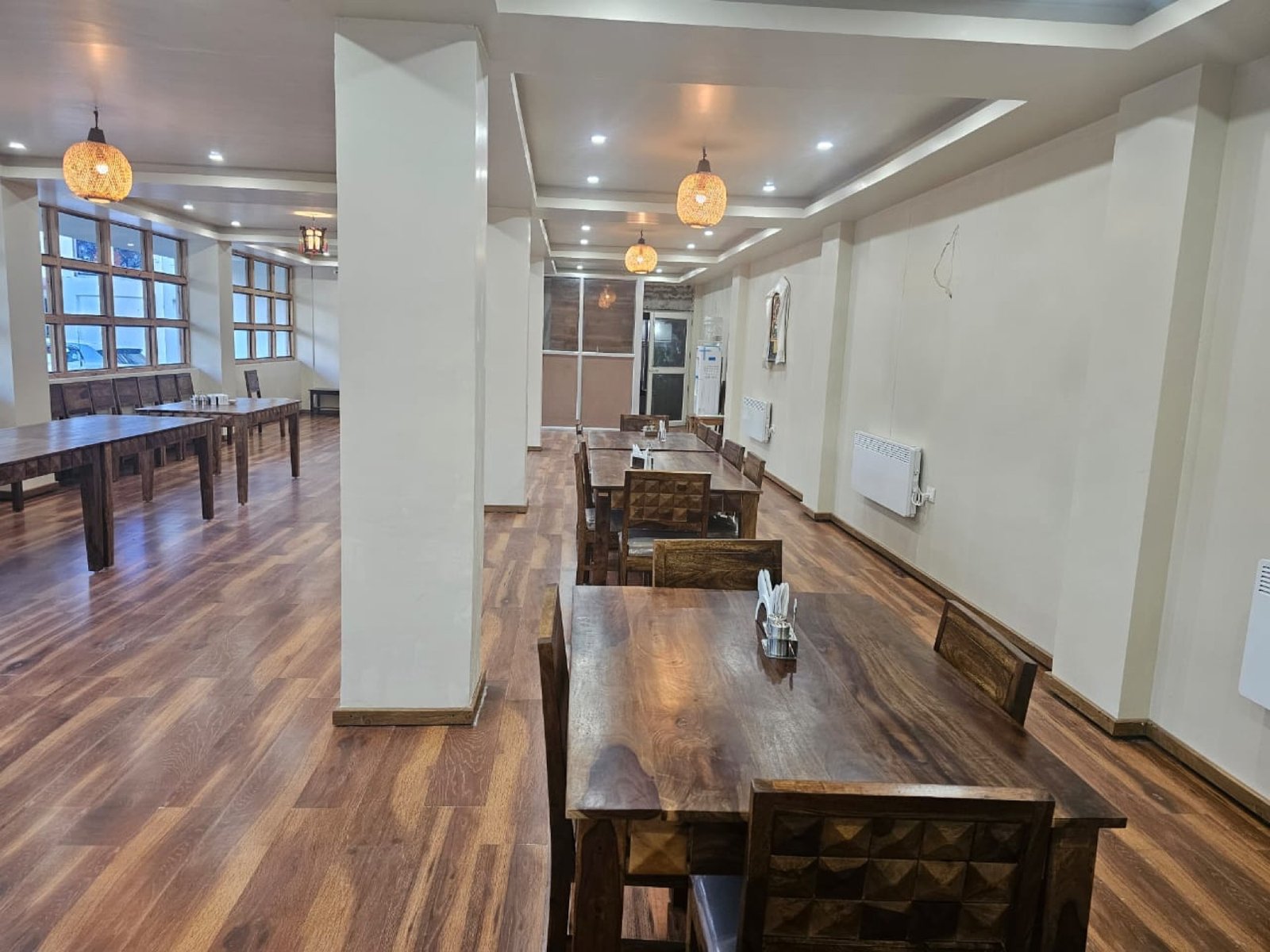 The dining hall at Hotel Taktsang from a second angle &mdash; hardwood floors and pendant lighting