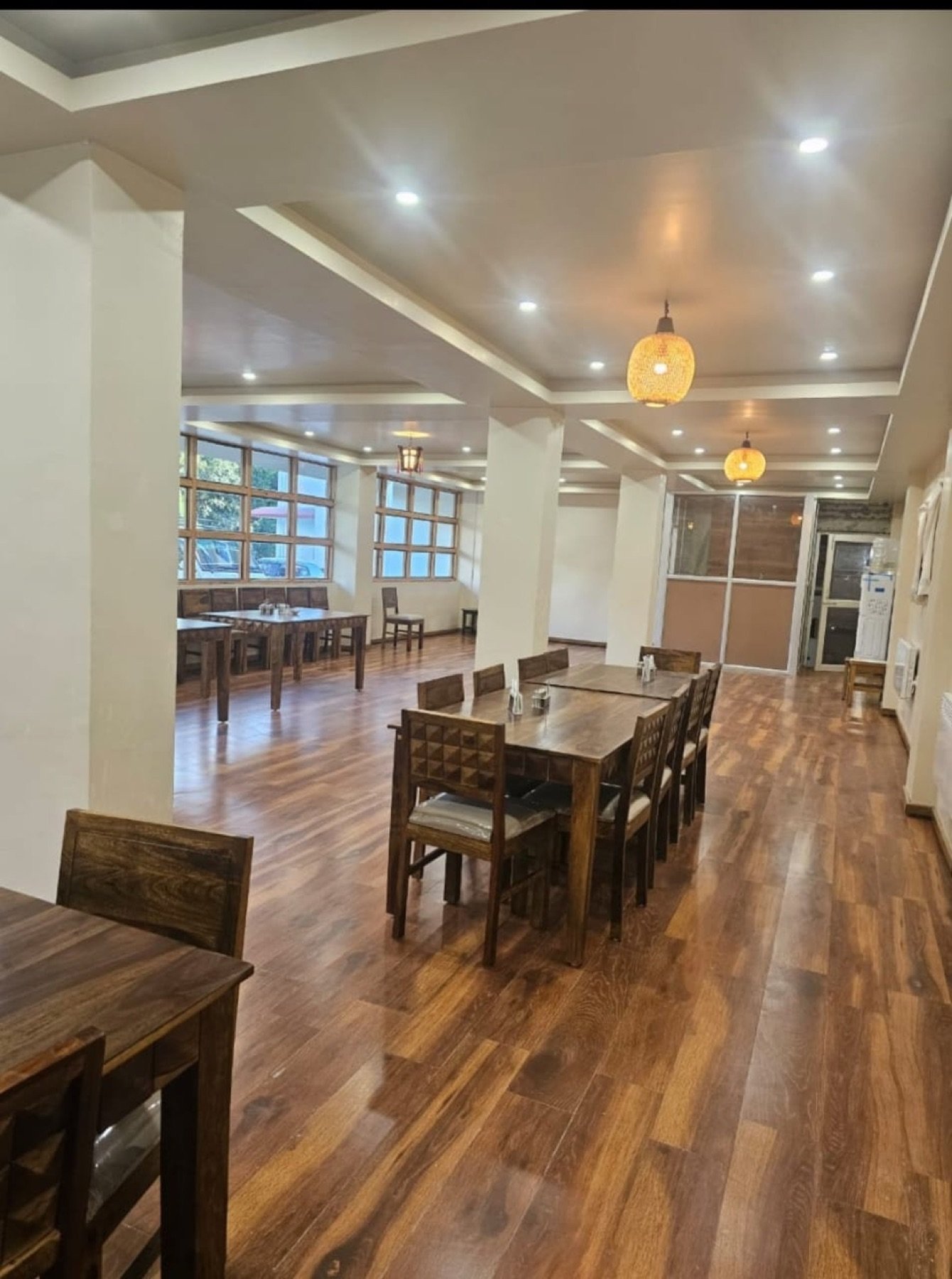 The dining hall at Hotel Taktsang &mdash; hardwood floor, pendant lamps, big windows
