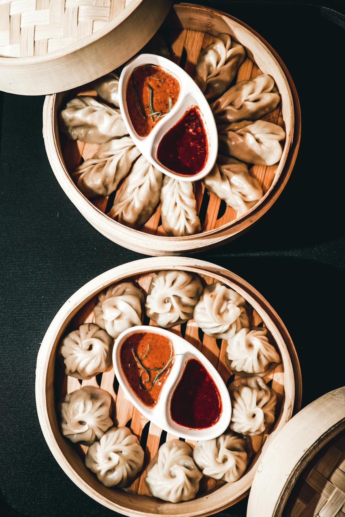 Two bamboo steamers of momos with red dipping sauces &mdash; from the Hotel Taktsang kitchen