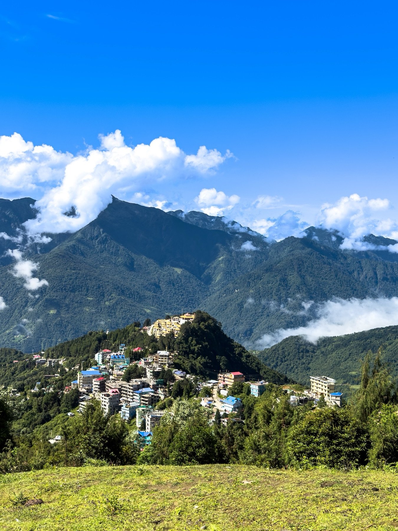 Tawang town on its ridge with cloud-capped peaks behind